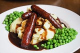 Sausage and mashed potatoes with peas.