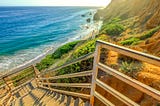 Secret secluded beach in Malibu, Los Angeles, California. Clear day with staircase leading down to a beautiful sandy beach with amazing rock formations.