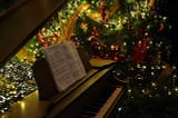 Piano and sheet music next to a Christmas tree
