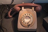 A beige, old model rotary telephone.