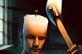Photo prompt. A human, candle. Candles wax and wick take the place of a forehead, and top of head completely, of a man, or woman. A hand is extended outwards, for point of view, and is holding a matchstick. Matchstick is lit up, and on fire. Matchstick on fire. Looks as if they are lighting their own wick, which is their head.