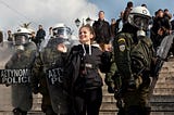 A student protester taunts Greek riot police in front of the Hellenic Parliament during Eurozone Crisis Protests in 2012.