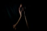 Women in the dark with hands covering face in fear