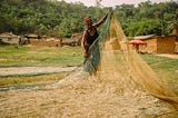 WOMAN COLLECTING THE SMALL FISH CAUGHT BY FISHING NETS AND SPREADING OUT IN NETS. Mama Dusor Agbenewoworle is a fish monger. Abume is one of the communities by the Volta Lake.