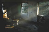 A dilapidated room without window coverings lets light into its darkness.