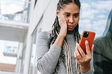 Concerned black woman using smartphone on street