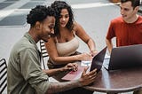 Happy young diverse friends watching video on contemporary laptop in cafeteria