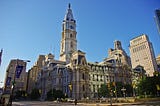 View of Philadelphia City Hall in central Philadelphia with buildings beside it, and blue skies behind it