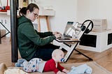 Woman working on laptop while watching her baby