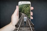 Man on a train track that runs into a phone held by a hand