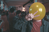 Still image from the short film Air Head showing a man at a party with a yellow balloon for a head.