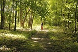 A woman standing on a sunny path in the forest