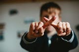 Young boy crossing his index fingers to form an “X”