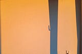Oranje licht van de namiddag op een muur en stopcontact met schaduwen van een raam.