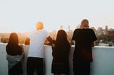 Group of young people overlooking a city from the top of a building