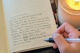 Custom Wellness Journal by Zenit with written entry, hand holding pen, and lit candle
