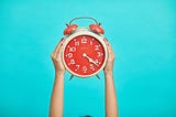 Colorful photo of a red alarm clock on a bright blue background