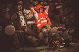Man leaning back on logs of wood he cut.