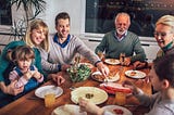 Extended family with parents, grandparents and children share a meal at a table.