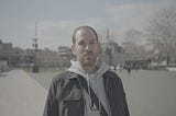 A man with hair loss standing outdoors in Istanbul, looking directly at the camera.