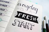 A notebook open to a page that reads “Every day is a fresh start”