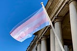 a trans flag fluttering in the sunshine at greenwhich uk