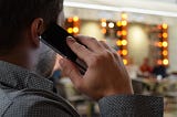 A man in his business office talking to a client on his cell phone. Using relationship marketing to bond with his clients.