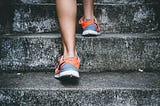 Woman in sneakers climbing stairs.