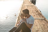 A father holding a young girl on a dock