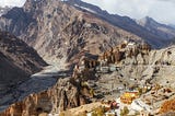 A barren looking small town sitting amongst dust brown mountains.