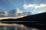 sunrise on the water with the clouds illumniated by the sun’s rays