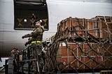 A solider getting ready to load crates of military aid for Ukraine onto a plane.