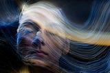 woman’s face with wavelike strands of light flowing over it from left to right