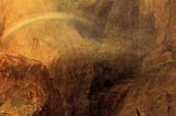 This is a photo of a painting by J.M.W. Turner from the 1800’s called “The Devil’s Bridge, St. Gothard.” It’s a blurry landscape mostly made up of rocky mountains with a stream running through it and a rainbow over the stream.
