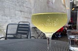 A glass of honey wine sits on a black outdoor bistro table. Image taken by author.