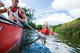 A man and a woman are canoeing on the river.