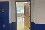 Classroom door in hallway showing empty room. Photo from author.
