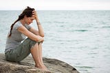 A woman sitting on a rock in despair