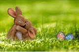 Two cute bunnies hugging and two foil wrapped Easter eggs