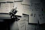 image of a robot sitting close to a lot of comments written on papers stuck to the wall