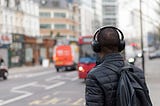 A man listening to headphones in a city street.
