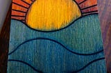 The lid of a handmade wooden box painted with a bright sunrise.