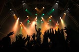 a silhouette image of people raising hands in a concert.