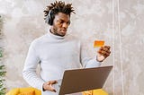 Man online shopping looking at his credit card.