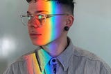 Side profile image of Nikki with prismatic rainbow light down their face