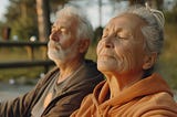 Two people with white hair tip their faces to the sky with their eyes closed.