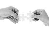 On a white background, two hands each holding a piece of jigsaw,. The two pieces look like they are about to fit together.