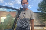 Declan standing next to the open car door in his Phantom Regiment t-shirt, his hair up in a topknot, Buddha-style.