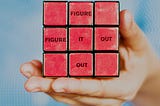 Red Rubiks cube written “figure it out”