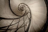 Black and white photo of the spiral railing of the staircase inside the Arc de Triomphe in Paris
